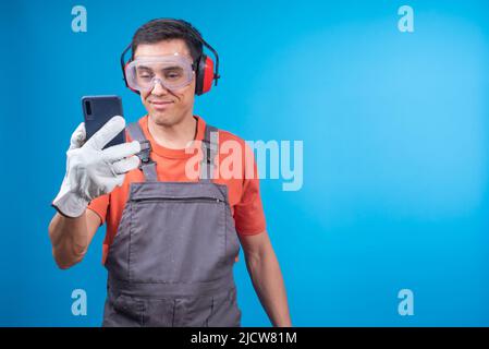 Positive craftsman in uniform reading message on smartphone Stock Photo