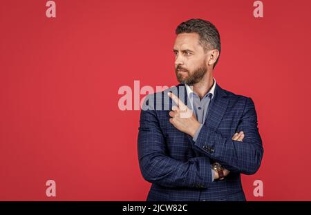 mature ambitious man businessman in businesslike suit pointing finger on copy space, suggestion Stock Photo