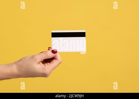 Profile side view closeup of human hand holding classic credit card, earning money, banking. Indoor studio shot isolated on yellow background. Stock Photo