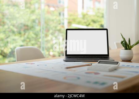 modern laptop computer with blank screen at workplace in office. finance report and calculator accounting on wooden table Stock Photo