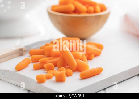 Baby carrot vegetable. Mini orange carrots on white table. Stock Photo