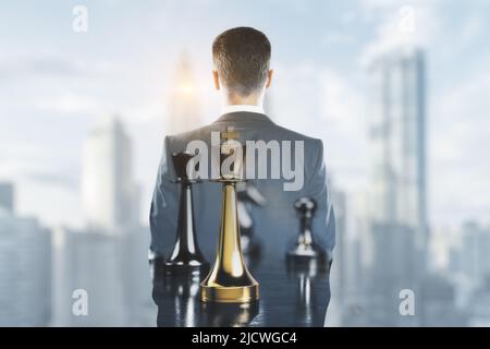 Business strategy and successful decisions concept with golden and silver chessmen on businessman back view looking at city skyline, double exposure Stock Photo