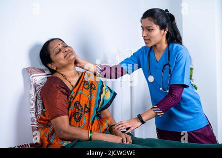 Nurse helping sick senior on bed to do exercise at home - concept of caretaker, assistance and rehabilitation Stock Photo