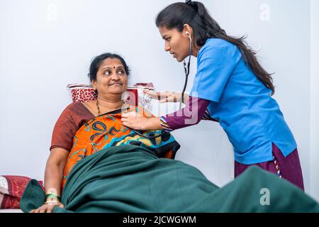 Nurse checking health of middle aged woman at nursing home using stethoscope - concept of routine checkups, caretaker and consultation Stock Photo