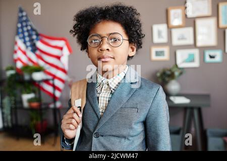 Portrait of African schoolkid in eyeglasses and uniform standing with backpack ready for going to school Stock Photo