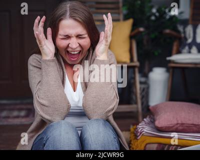 middle aged depressed woman sitting on porch. She feeling sad and worried suffering depression in mental health. Problems and broken heart concept. Negative human emotion with cry of pain Stock Photo