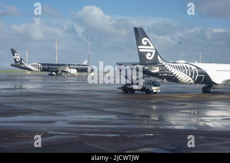 Auckland New Zealand - June 13 2022: White and black Air New zealand planes parked on tarmac. at Auckland Airport after rain. Stock Photo