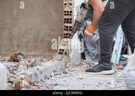 Unrecognizable man using a jackhammer to drill into wall. Stock Photo
