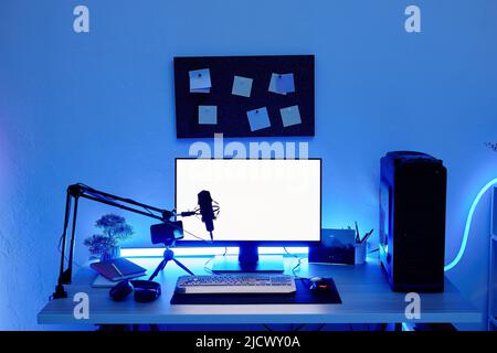 Background image of gaming setup PC on desk lit with blue neon lighting, screen mockup Stock Photo