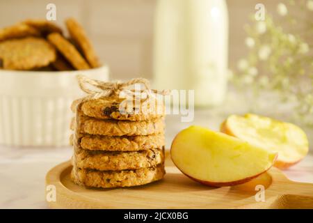 Oatmeal cookies with oats, apple, nuts and wholemeal flour free on an wooden background. A stack of oatmeal cookies tied with string on side view. Sid Stock Photo