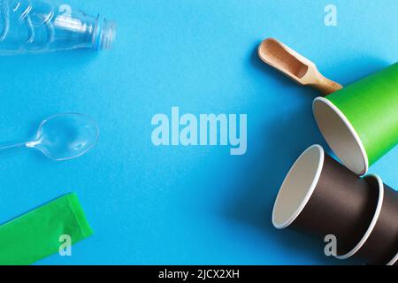 paper vs plastic. Eco-friendly disposable tableware made of and paper on a blue background. Plastic harmful dishes and cutlery Stock Photo