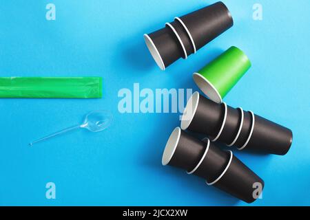 paper vs plastic. Eco-friendly disposable tableware made of and paper on a blue background. Plastic harmful dishes and cutlery Stock Photo