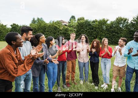 Young diverse people celebrating together outdoor - Focus on blond guy face Stock Photo