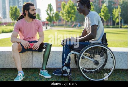 Happy friends with disability having fun at park city - Focus on African man sitting on wheelchair Stock Photo