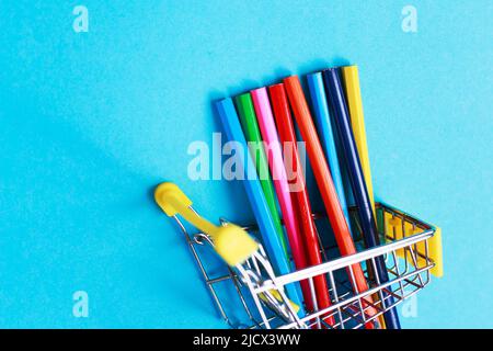 shopping cart with colored pencils on blue background Stock Photo