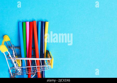 shopping cart with colored pencils on blue background Stock Photo