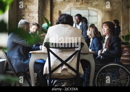 Multiracial business people working inside office - Focus on asian woman sitting on wheelchair Stock Photo