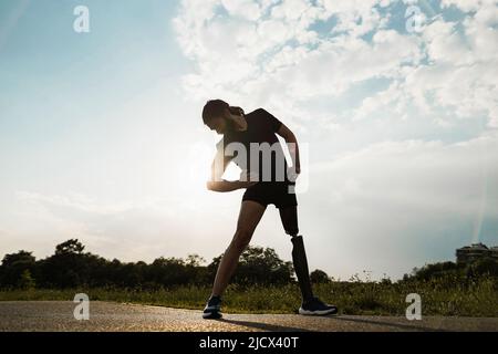 Young fit man with prosthetic leg doing stretching day routine outdoor - Focus on left shoe Stock Photo