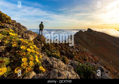 Man watching the mist at sunrise standing on rocks on Pico de la Zarza mountain peak, Fuerteventura, Canary Islands, Spain, Atlantic, Europe Stock Photo