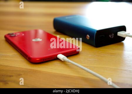 30 April 2021 Eskisehir Turkey. Red iphone 11 being charged by powerbank on wooden table Stock Photo