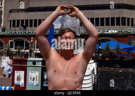 UK Tom trying to cool down with a bag of ice on another balmy sunny day on Brighton Beach. Temperature upto 28c, summer has arrived. 16th June 2022. David Smith/Alamynews Stock Photo