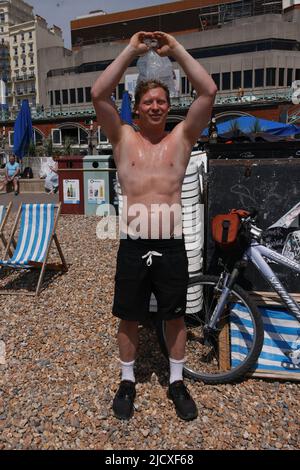 UK Tom trying to cool down with a bag of ice on another balmy sunny day on Brighton Beach. Temperature upto 28c, summer has arrived. 16th June 2022. David Smith/Alamynews Stock Photo