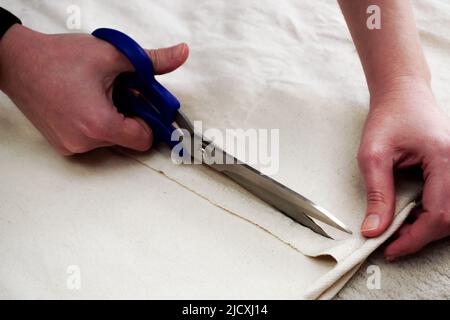 Woman measuring and cutting fabric at home close up view Stock Photo