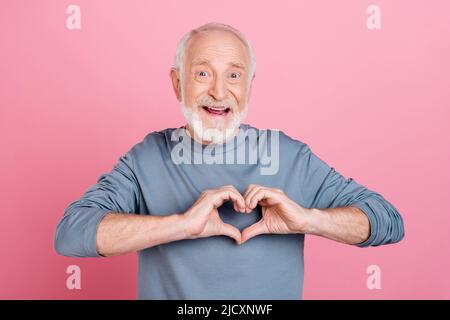 Photo of excited funky guy pensioner dressed grey pullover showing arms heart isolated pink color background Stock Photo