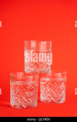 crystal glasses with clear water stacked on bright red background Stock Photo