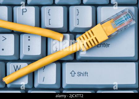 Internet connection disconnected. Blue computer keyboard with yellow network cable cutted off Stock Photo
