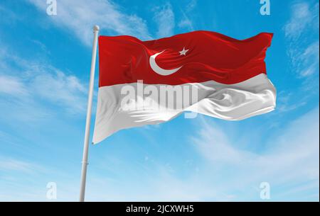 official flag of Islamic State  Indonesia at cloudy sky background on sunset, panoramic view. Indonesian travel and patriot concept. copy space for wi Stock Photo