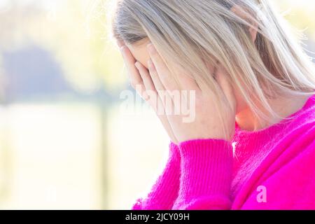Sad tired young woman touching forehead having headache migraine or depression, upset frustrated girl troubled with problem feel stressed cover crying face with hand suffer from grief sorrow concept. High quality photo Stock Photo