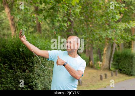 Funny selfie of a hairless white man making a video call in nature and smiling at the camera Stock Photo