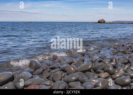 Scenic Sea View of Greencliff Beach, With Wet Pebbles, Exposed Rocks and Coastal View Towards Croyde at Mid Tide: Greencliff, Near Bideford Stock Photo