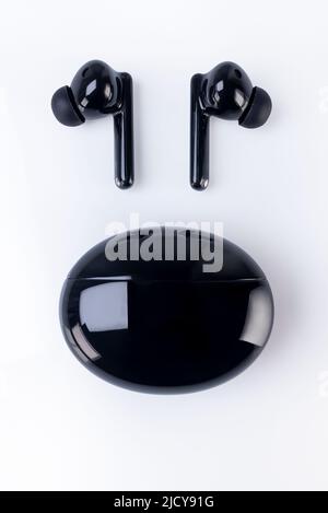 Wireless headphones on a white background. Headset close up in the charging case close-up. Stock Photo