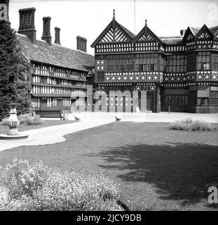 1940s, historical, Bramall Hall, Bramhall, Stockport, England, UK. A timber-framed Tudor manor house that dates back to the 14th century, with later additions, the house and surrounding parkland was acquired by the local authority in 1935 and became a museum. The Davenport family, which it is believed built the house, held the manor for over 500 years. Here we see a view from the 1940s from the west, of the main entrance, courtyard, south wing and the Great Hall in the centre. Stock Photo