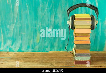 audio book concept with stack of books and vintage headphones on teal background ,good copy space. Stock Photo