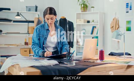 A Professional Fashion Designer Creates a New Collection, Draws, Works with Sketches Using a Laptop in a Fashion Business Startup Studio. Concept of H Stock Photo