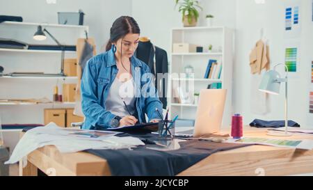 A Professional Fashion Designer Creates a New Collection, Draws, Works with Sketches Using a Laptop in a Fashion Business Startup Studio. Concept of H Stock Photo