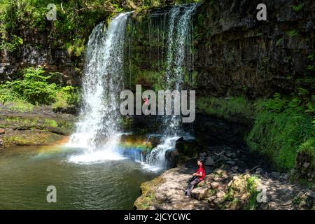 Walkers and visitors to the Brecon Beacons National Park in Wales walking behind Sgwd Yr Eira. a spectacular waterfall on the Afon Hepste river Stock Photo