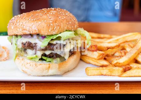 A Brewers Fayre Big stack Burger served in one of the chains uk restaurants with french fries. A tasty but high calorie meal option Stock Photo