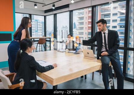 Multiethnic creative group of business people brainstorming and using sticky notes on partition desk in modern office at business district Stock Photo