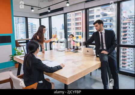 Multiethnic creative group of business people brainstorming and using sticky notes on partition desk in modern office at business district Stock Photo