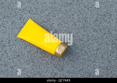 Yellow cream tube on a gray texture background. Stock Photo