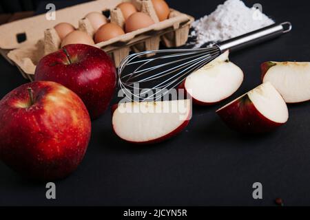 Ingredients for apple pie are on the kitchen table: eggs, flour, whisk, apples, ingredients, products Stock Photo
