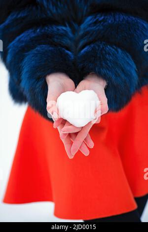 Close up Faceless Woman Girl Holds Heart Shaped Snowball in Hand Outdoor. Love concept. Valentine day background. Stock Photo