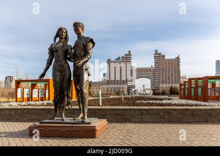 Nur Sultan (Astana), Kazakhstan, 11.11.21. Bronze sculpture of man and woman in Lovers Park in Nur Sultan with city skyline in the background. Stock Photo