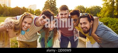 Portrait of joyful multiracial friends having good time relaxing together in summer park. Stock Photo