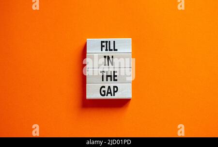 Fill in the gap symbol. Concept words Fill in the gap on wooden blocks on a beautiful orange table orange background. Business, motivational and fill Stock Photo