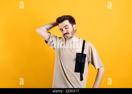 Caucasian man wearing beige tee posing isolated over yellow background touching head in despair, disappointed. Emotionally reacting to failure, standi Stock Photo